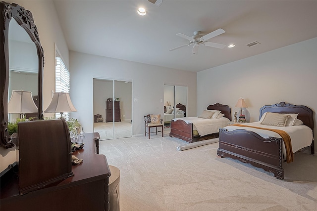 bedroom featuring ceiling fan, light carpet, and two closets