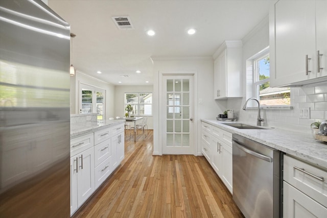 kitchen featuring decorative backsplash, stainless steel appliances, white cabinetry, and sink