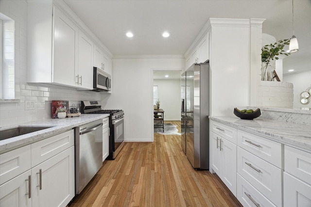 kitchen with stainless steel appliances, crown molding, pendant lighting, light hardwood / wood-style floors, and white cabinets