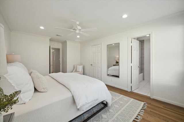 bedroom featuring ceiling fan, wood-type flooring, crown molding, and connected bathroom