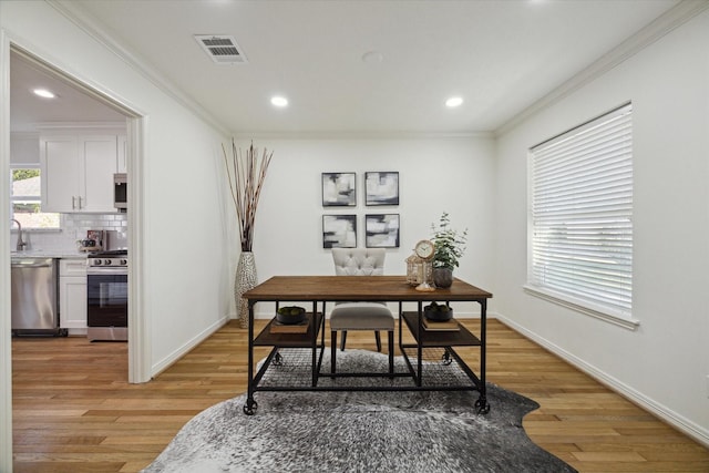 home office with sink, ornamental molding, and light wood-type flooring