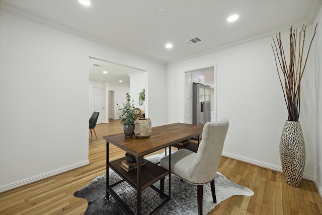 dining room featuring crown molding and light hardwood / wood-style flooring