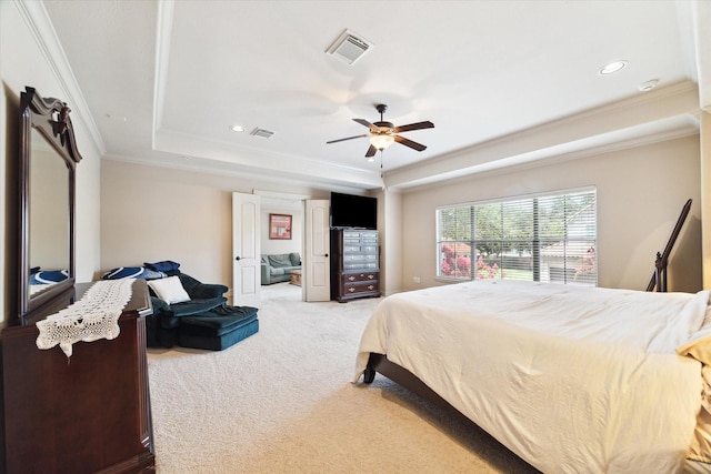 bedroom with ceiling fan, carpet floors, ornamental molding, and a tray ceiling