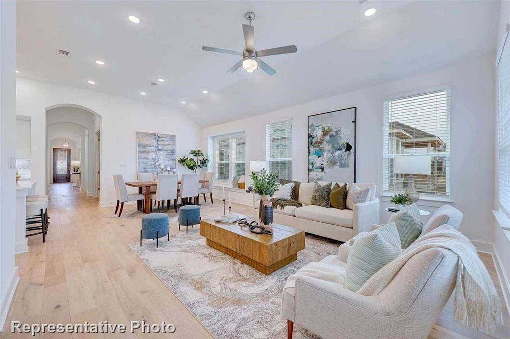 living room featuring ceiling fan, vaulted ceiling, and light hardwood / wood-style flooring