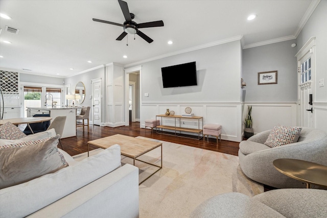 living room featuring dark wood-type flooring, ceiling fan, ornamental molding, and sink