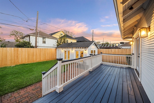 deck at dusk featuring a lawn and an outbuilding