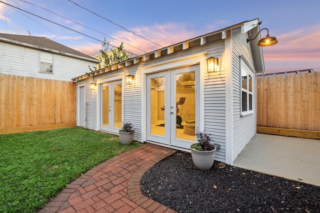 outdoor structure at dusk with french doors and a yard