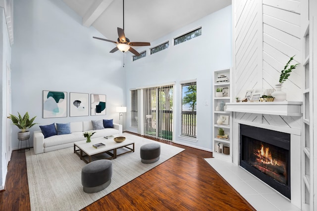 living room with hardwood / wood-style flooring, a fireplace, beam ceiling, and a high ceiling