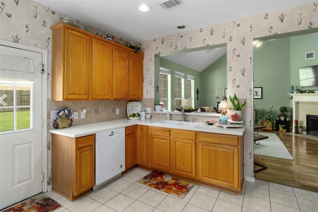 kitchen with kitchen peninsula, backsplash, white dishwasher, sink, and light tile patterned floors