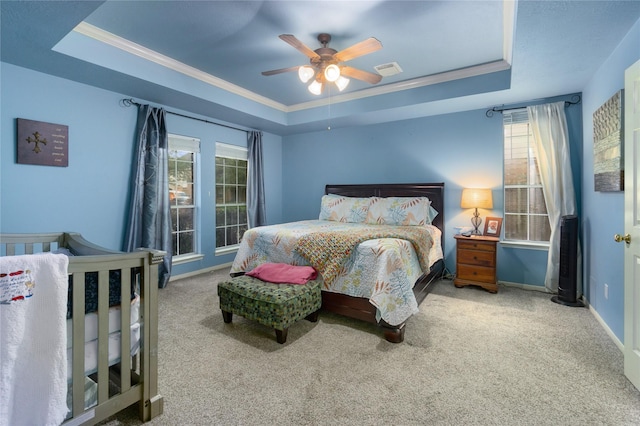 carpeted bedroom with ceiling fan, ornamental molding, and a tray ceiling