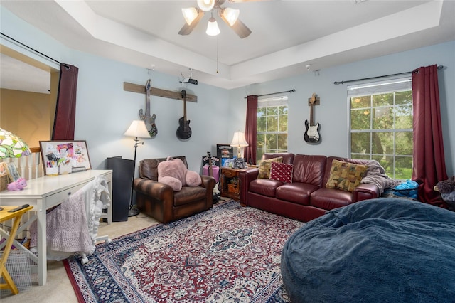 carpeted living room featuring a wealth of natural light, a raised ceiling, and ceiling fan