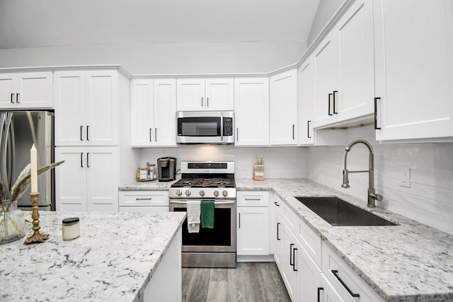 kitchen featuring stainless steel appliances, white cabinetry, tasteful backsplash, and sink