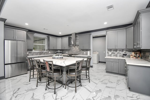 kitchen featuring gray cabinetry, sink, wall chimney range hood, and stainless steel appliances