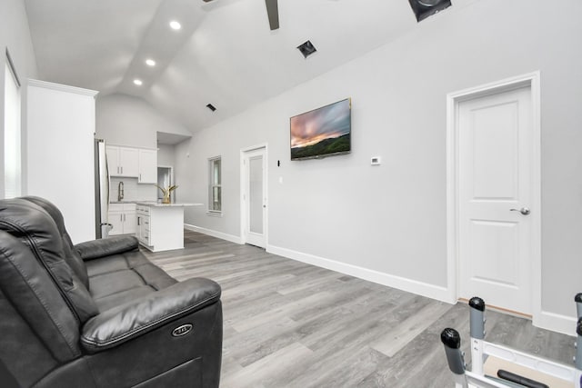 living room with light hardwood / wood-style floors, vaulted ceiling, and ceiling fan