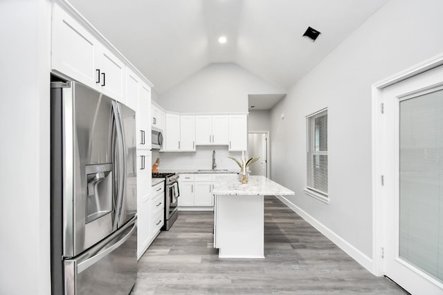 kitchen featuring white cabinetry, sink, light stone countertops, a center island with sink, and appliances with stainless steel finishes