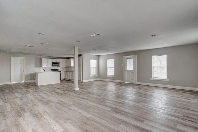 unfurnished living room featuring light hardwood / wood-style floors and sink