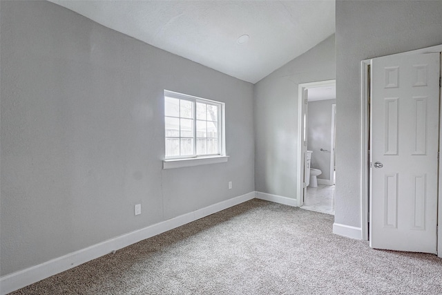 unfurnished bedroom featuring ensuite bathroom, lofted ceiling, and carpet floors