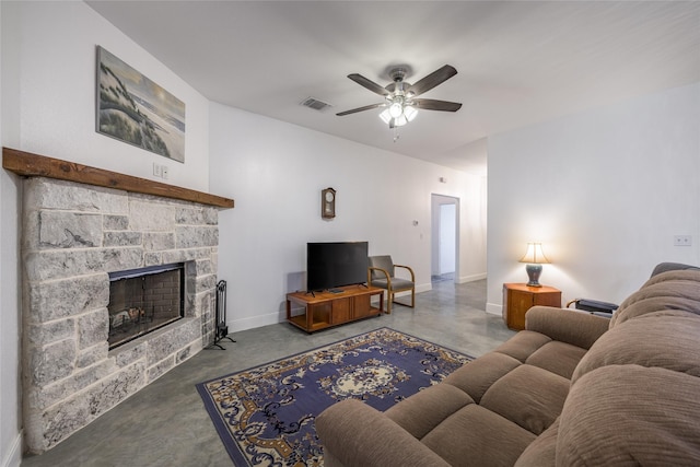 living room with concrete flooring, a stone fireplace, and ceiling fan