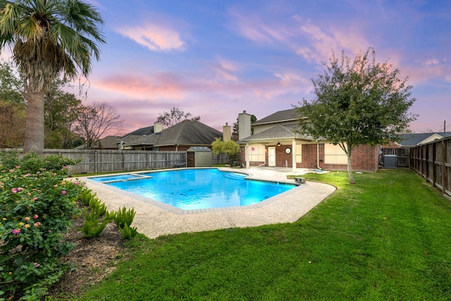 pool at dusk with a yard, ceiling fan, and central air condition unit