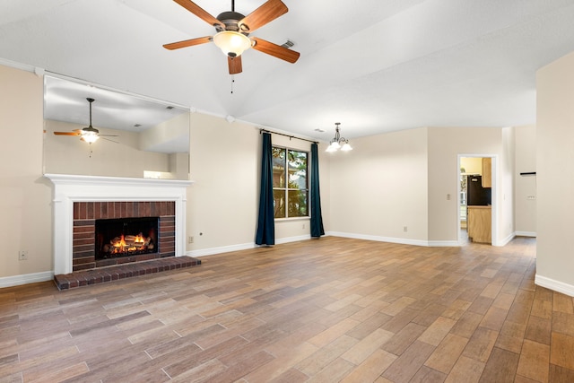 unfurnished living room with ceiling fan with notable chandelier, a brick fireplace, and lofted ceiling