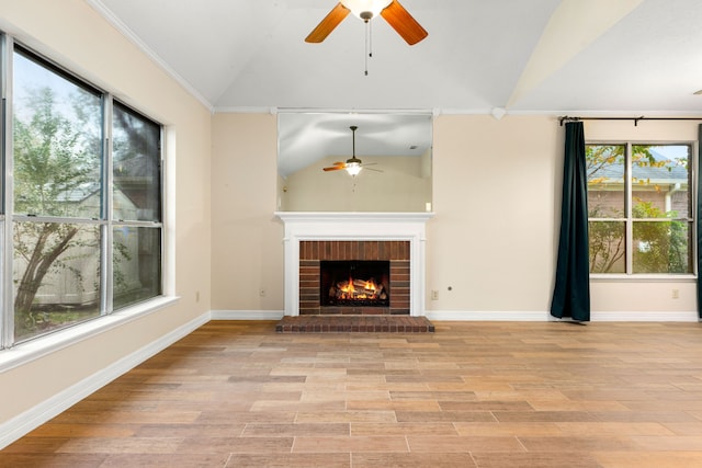 unfurnished living room featuring plenty of natural light, light wood-type flooring, vaulted ceiling, and a brick fireplace