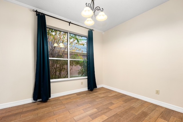 unfurnished room featuring ornamental molding, light hardwood / wood-style flooring, and an inviting chandelier