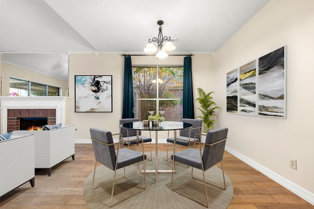 dining room featuring a notable chandelier, light hardwood / wood-style floors, crown molding, and a fireplace