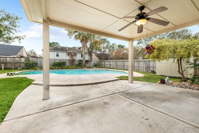 view of swimming pool featuring a lawn, ceiling fan, and a patio