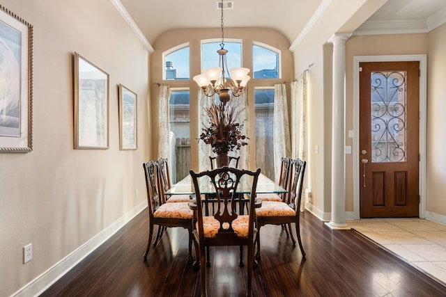 dining room featuring hardwood / wood-style floors, lofted ceiling, ornate columns, ornamental molding, and a chandelier