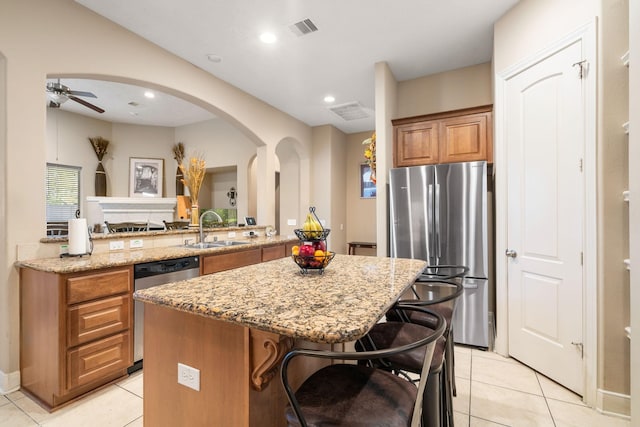 kitchen with a breakfast bar, sink, light tile patterned floors, appliances with stainless steel finishes, and a kitchen island