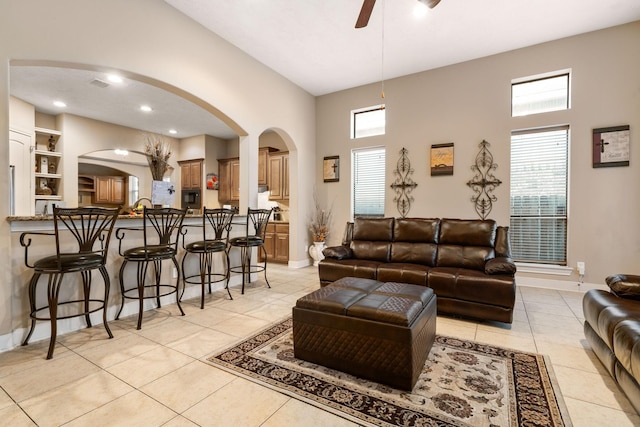 living room featuring ceiling fan, light tile patterned floors, and a high ceiling