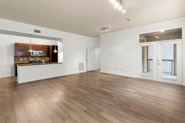 unfurnished living room featuring french doors, light hardwood / wood-style flooring, and track lighting