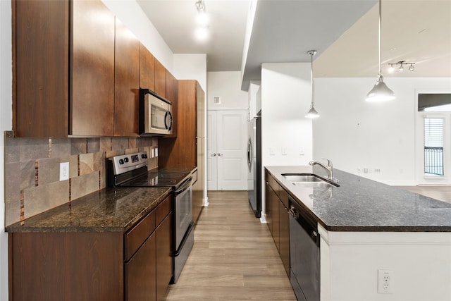 kitchen featuring pendant lighting, sink, decorative backsplash, dark stone countertops, and appliances with stainless steel finishes