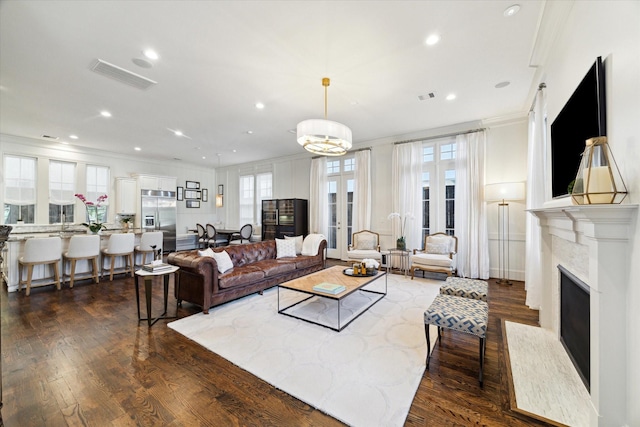 living room featuring dark hardwood / wood-style floors, crown molding, a fireplace, and a wealth of natural light