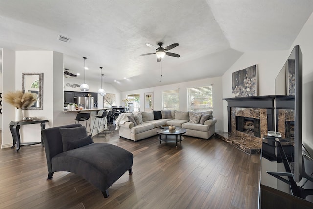 living room with ceiling fan, dark wood-type flooring, a textured ceiling, vaulted ceiling, and a fireplace