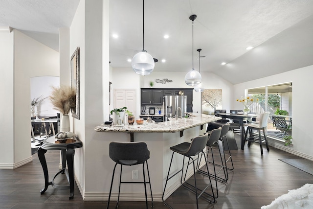 kitchen featuring vaulted ceiling, light stone countertops, decorative light fixtures, a kitchen bar, and stainless steel fridge with ice dispenser