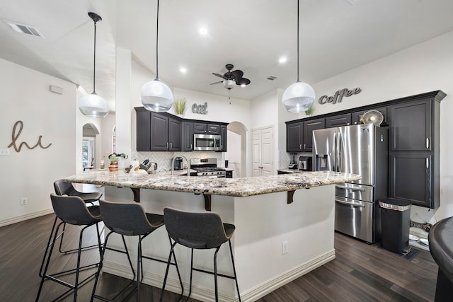 kitchen featuring pendant lighting, light stone counters, stainless steel appliances, and tasteful backsplash