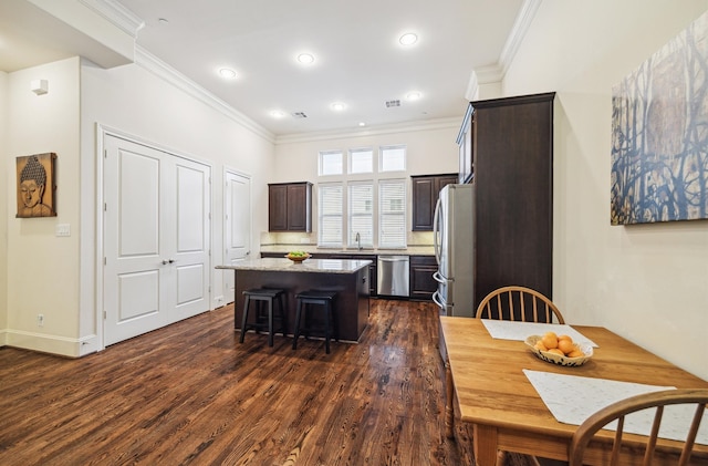 kitchen with dark hardwood / wood-style floors, a center island, appliances with stainless steel finishes, a breakfast bar area, and dark brown cabinets