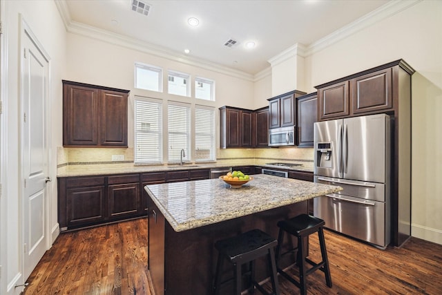 kitchen with appliances with stainless steel finishes, a center island, tasteful backsplash, sink, and dark hardwood / wood-style floors