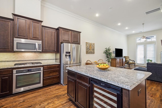 kitchen featuring dark brown cabinets, beverage cooler, stainless steel appliances, and a kitchen island