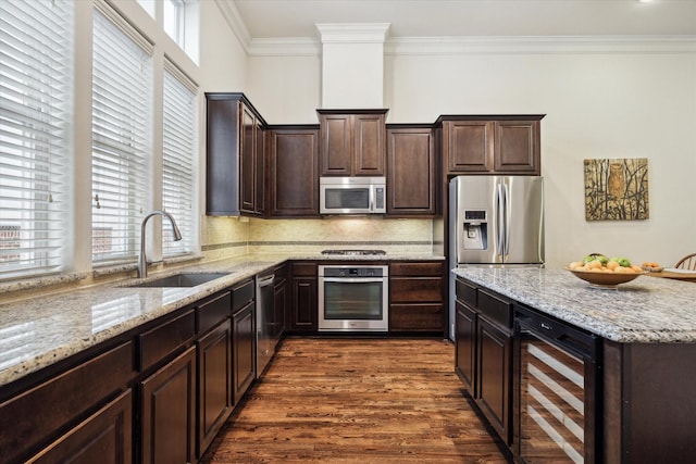 kitchen with stainless steel appliances, backsplash, dark brown cabinets, wine cooler, and sink