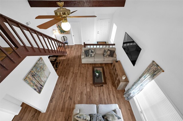 living room featuring hardwood / wood-style flooring, ceiling fan, and beam ceiling