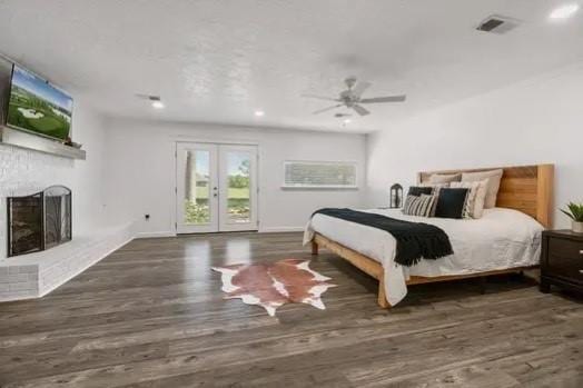 bedroom with ceiling fan, dark hardwood / wood-style floors, a fireplace, and access to outside