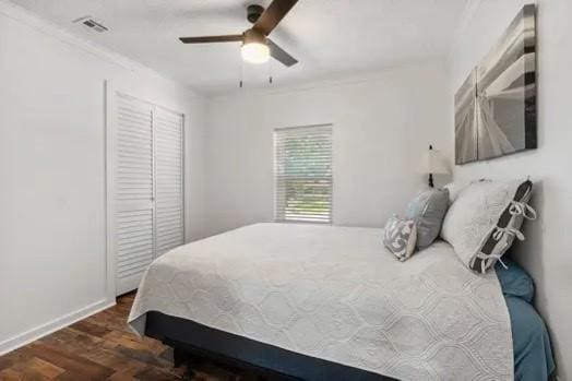 bedroom featuring a closet, dark hardwood / wood-style floors, ceiling fan, and ornamental molding