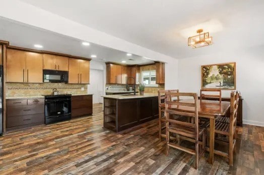 kitchen with tasteful backsplash, dark hardwood / wood-style flooring, sink, and black appliances