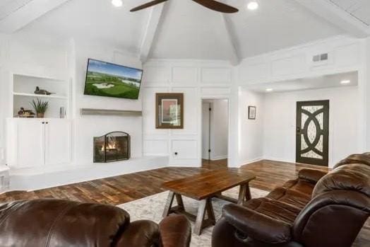 living room with built in shelves, ceiling fan, a large fireplace, vaulted ceiling with beams, and wood-type flooring