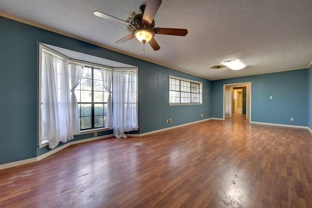 empty room with hardwood / wood-style floors, plenty of natural light, and a textured ceiling