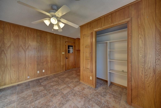 unfurnished bedroom with ceiling fan and wood walls