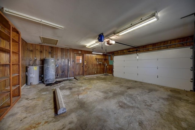 garage with water heater, wooden walls, and a garage door opener