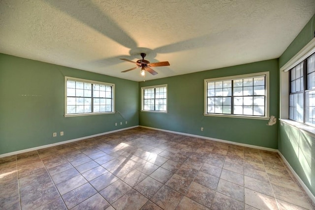 tiled empty room featuring ceiling fan and a textured ceiling